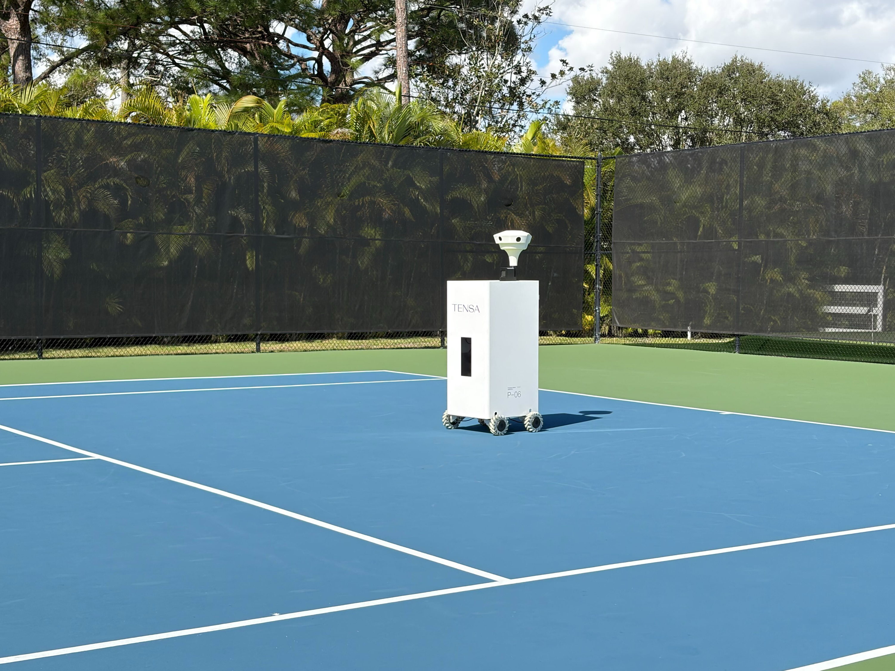 The Tensa AI Tennis Ball Machine - A sleek, professional training partner on a tennis court